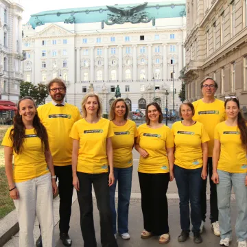 (ns)Yellow September Team der Gesundheit Österreich. © Gesundheit Österreich / Georg Gatnar Acht Personen im gelben T-Shirt posieren vor der Wiener Ringstraße für ein Gruppenbild.