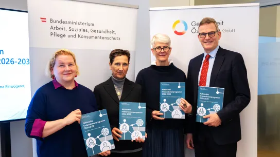 © BMASGPK/David Habermann Vier Personen stehen vor Roll-ups von BMASGPK und Gesundheit Österreich GmbH (GÖG) und halten die Broschüre „Nationales Krebsrahmenprogramm 2026–2035“ in die Kamera.